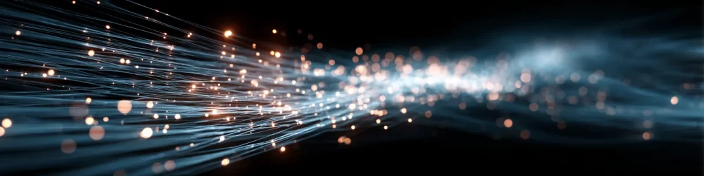 Abstract visualization of glowing fiber optic strands carrying data, with luminous light particles representing digital information flow