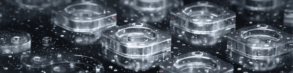 Panoramic close-up of precision-machined transparent optical components on a speckled cleanroom surface, representing advanced photonics and semiconductor manufacturing technology.