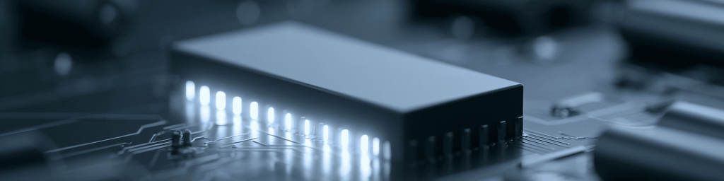 Panoramic close-up of a monochrome blue microchip with glowing connectors on a circuit board, representing advanced computing power and modern semiconductor technology.