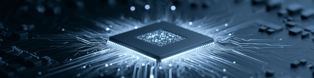 Panoramic close-up of a monochrome blue microchip with a glowing core and light trails on a circuit board, representing advanced computing and semiconductor technology.