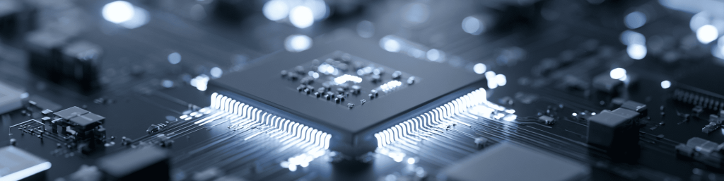 Panoramic close-up of a monochrome microprocessor with glowing silver connectors on a circuit board, representing advanced computing power and semiconductor technology.