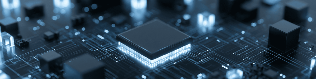 Wide panoramic macro view of a square central semiconductor chip with glowing bright pin edges, set amid intricate circuit traces and surrounding compact components in cool dark blue monochrome.